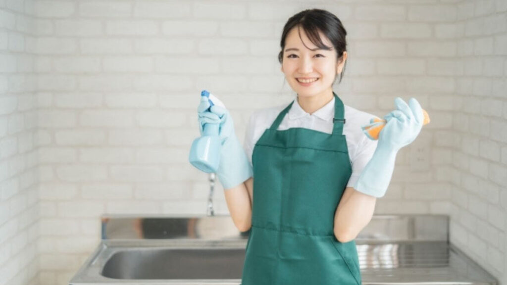 スポンジと洗剤を持ち笑顔のクリーニング業者の女性
