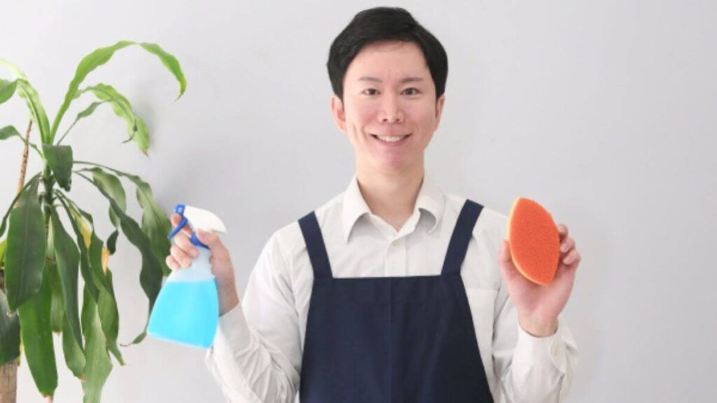 スポンジと洗剤を持つエプロン姿の男性