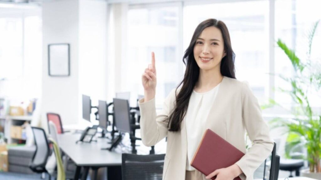 パソコンを持ちオフィスで働くスーツ姿の女性
