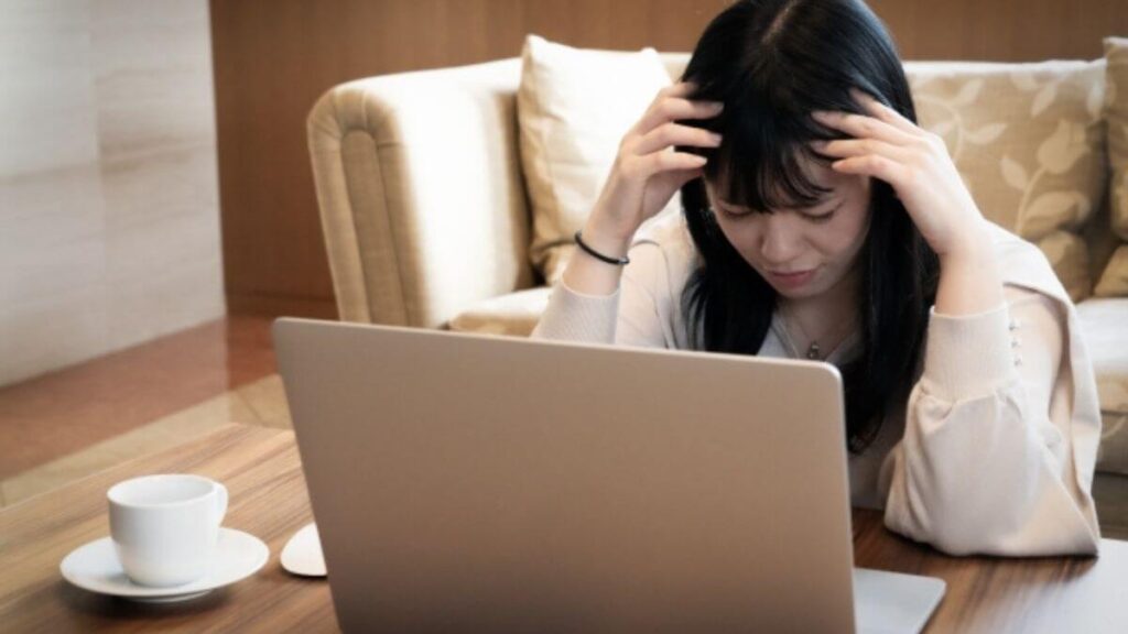 パソコンの前で頭を抱える若い女性