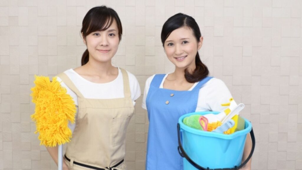 掃除道具を持ち笑顔のクリーニング業者の女性2人