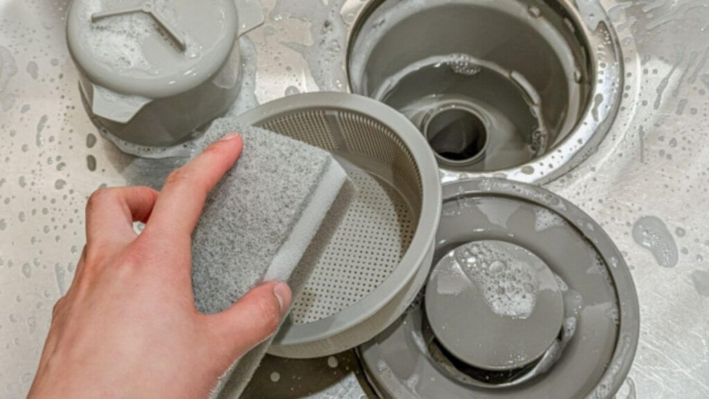 キッチンの排水溝を掃除している女性