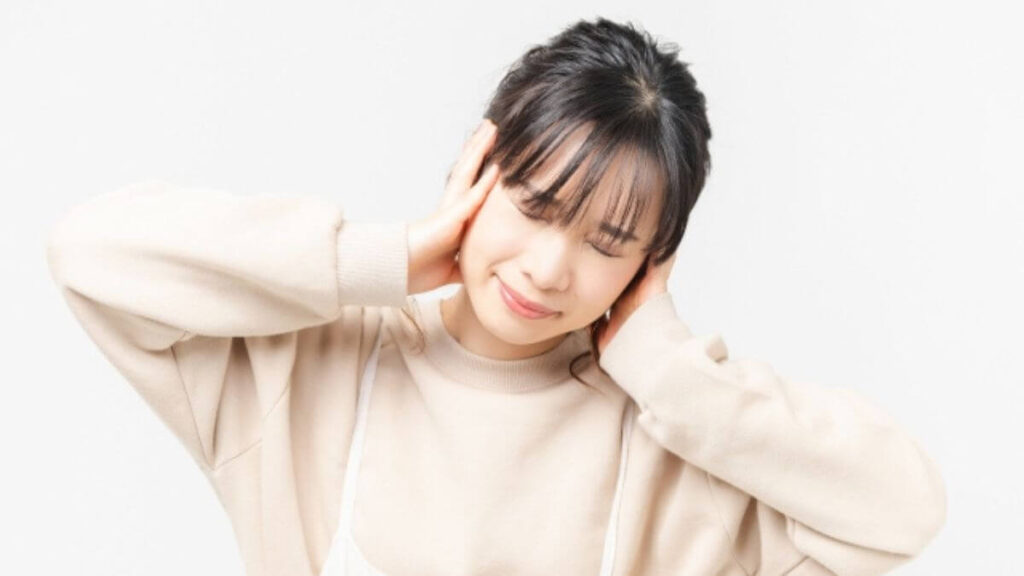 両手で頭を押さえる若い女性