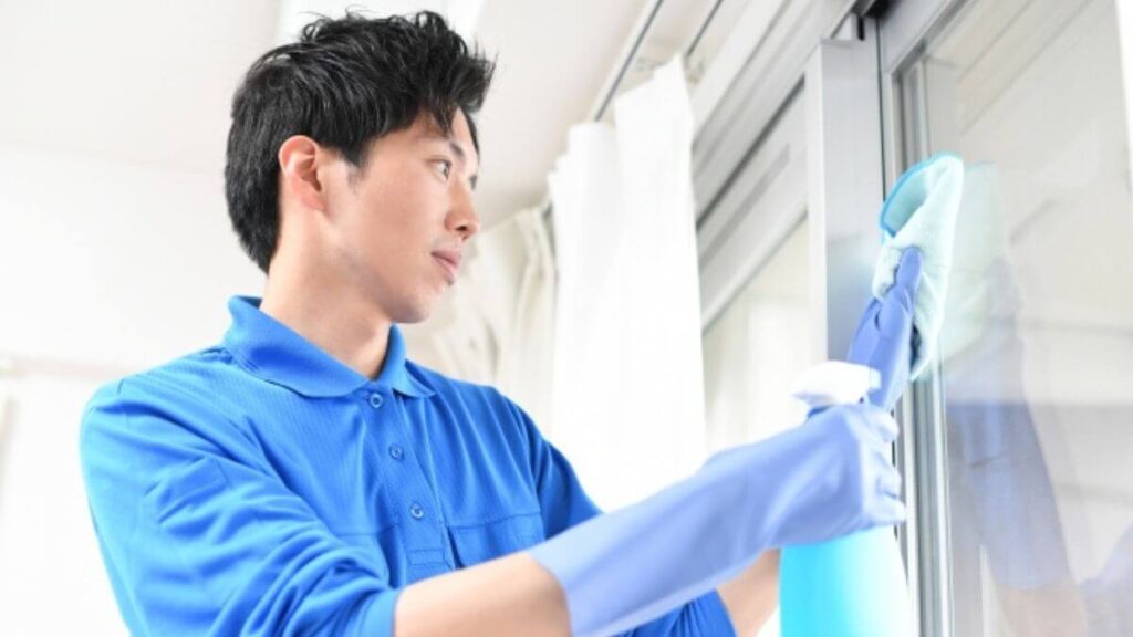 窓を掃除するハウスクリーニング業者の男性