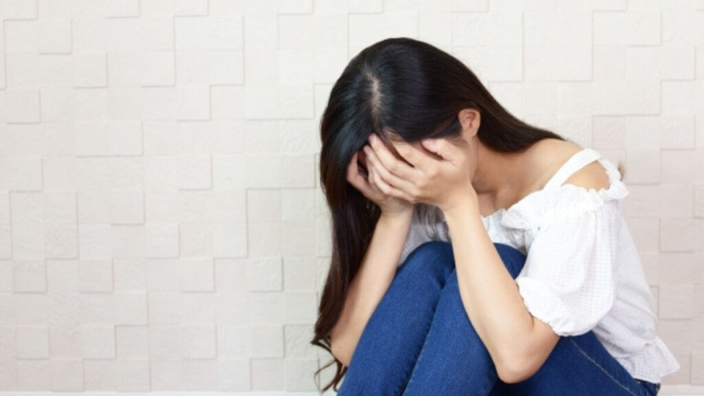部屋の隅でうずくまり落ち込む女性