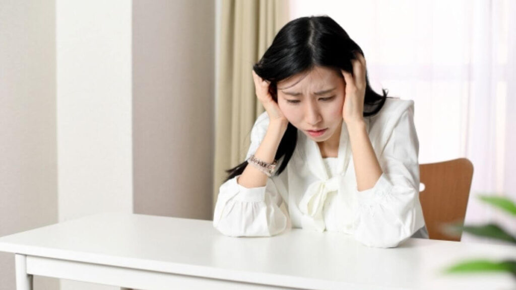 頭を抱えて悩んでいる若い主婦