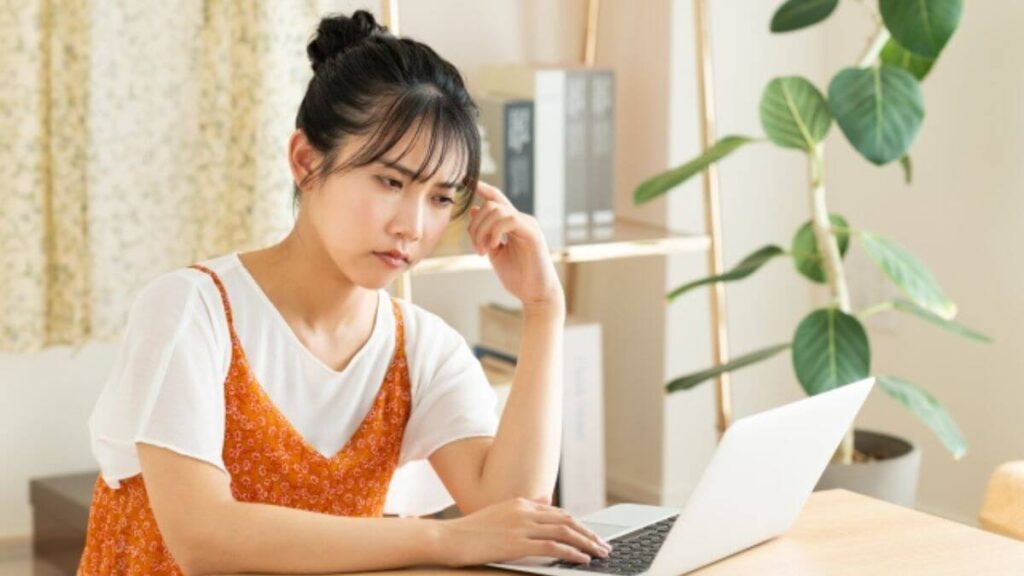 パソコンを見ながら考え事をする若い女性