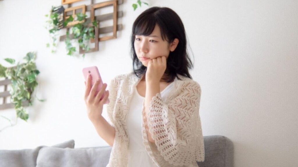 スマホを持って悩む若い女性