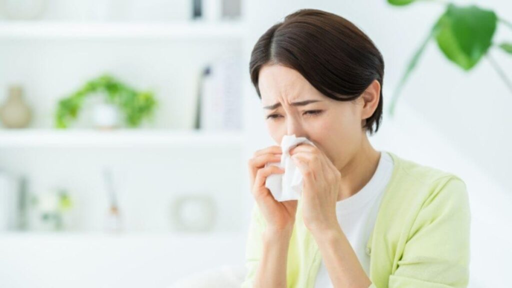 部屋で鼻を押さえて体調が悪そうな女性