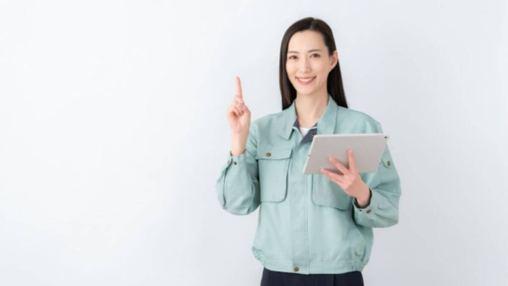 指をあげ説明をする作業着姿の若い女性