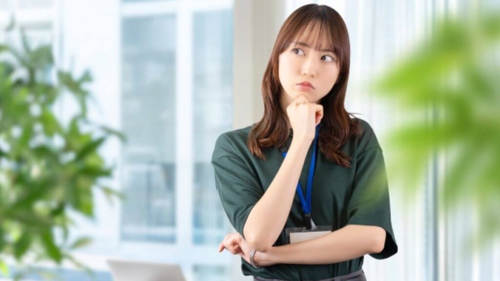 腕を組み考え事をする若い女性