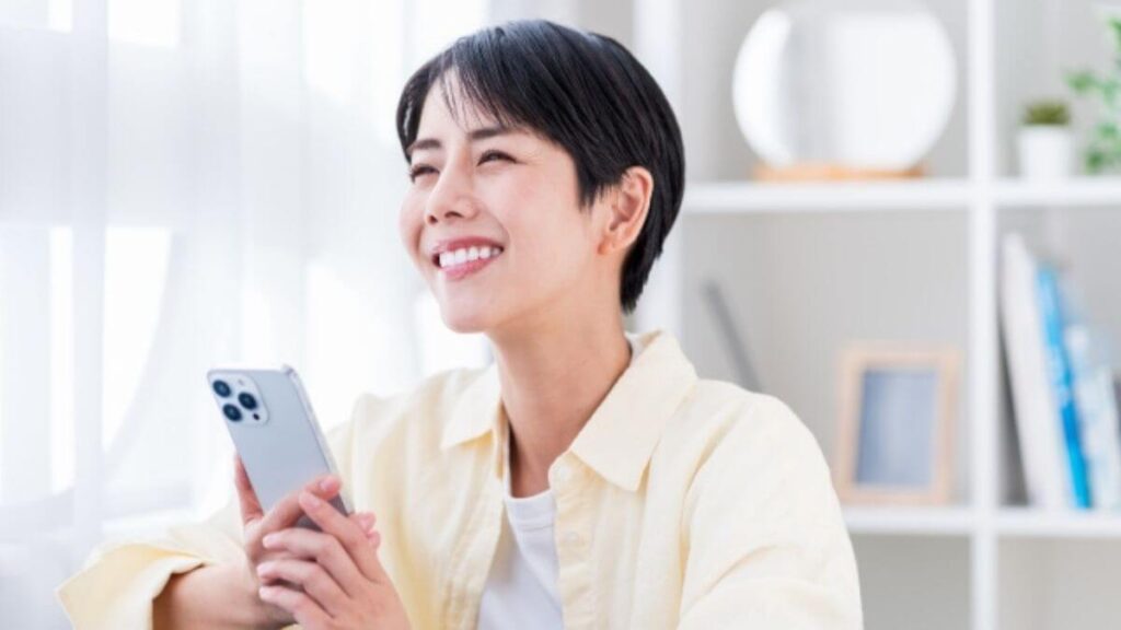 スマホを片手に微笑む若い女性