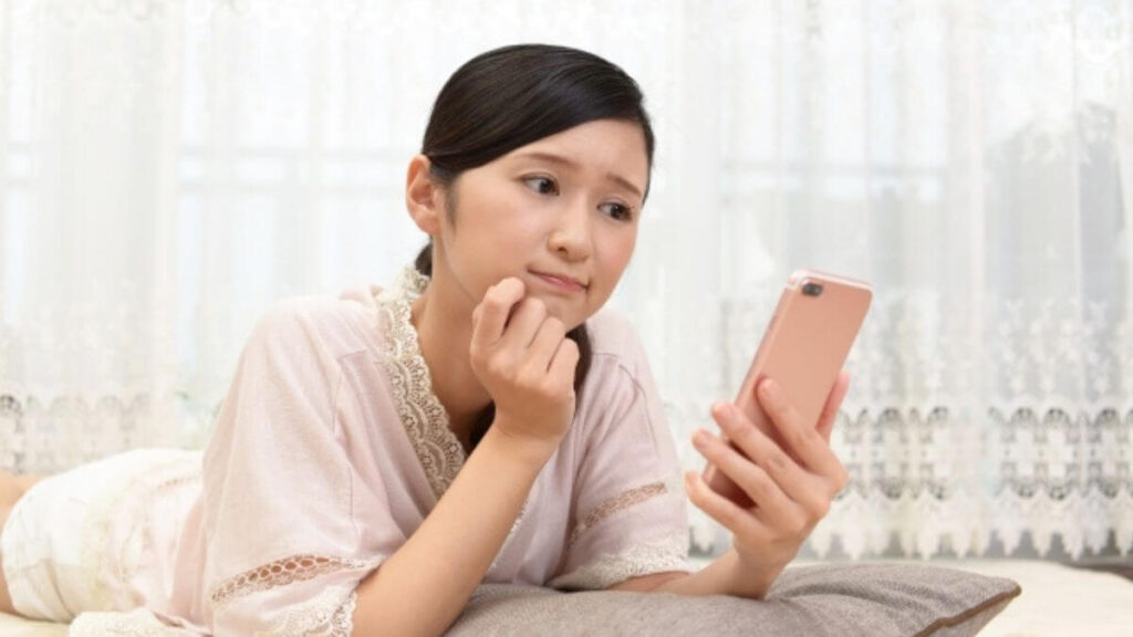 スマホを片手に難しい表情をする女性