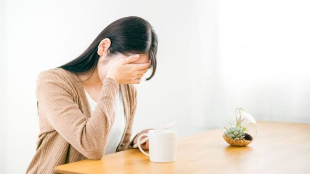 部屋で頭を抱え体調が悪そうな女性