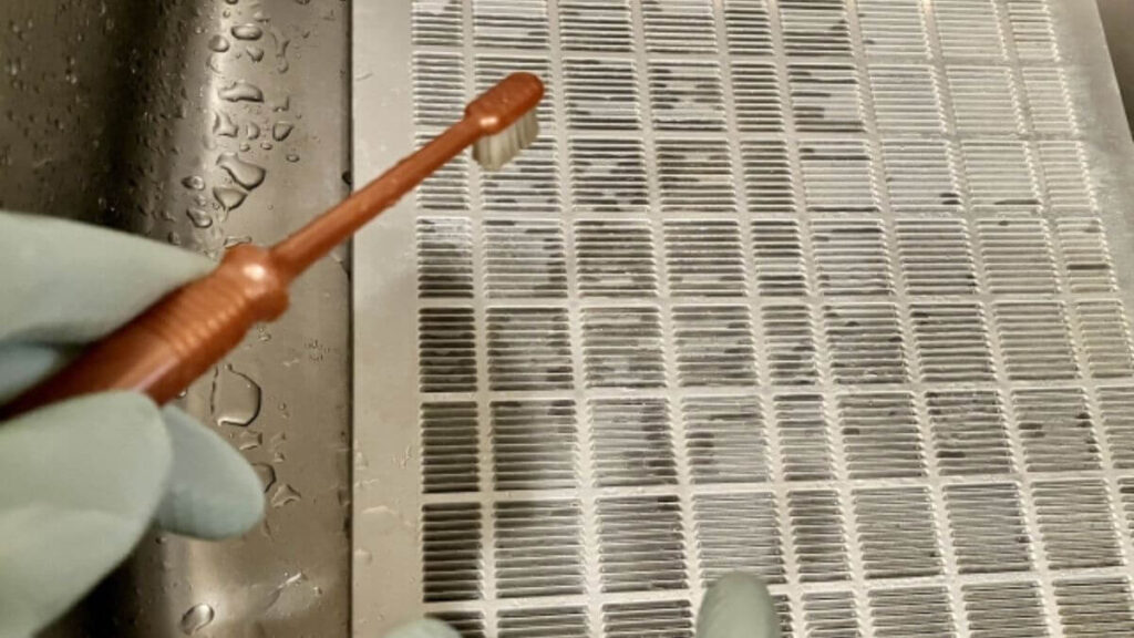 換気扇の部品を歯ブラシを使って掃除する様子