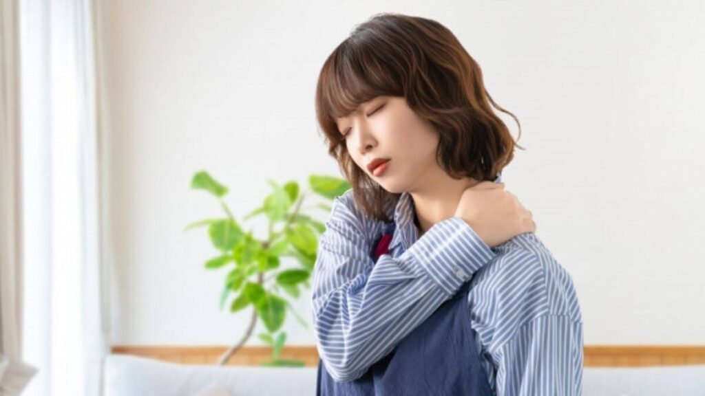 疲れから肩を抑える若い女性