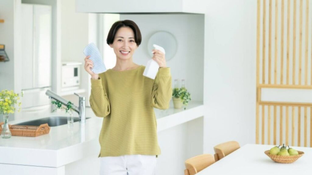掃除道具を持ち笑顔の女性