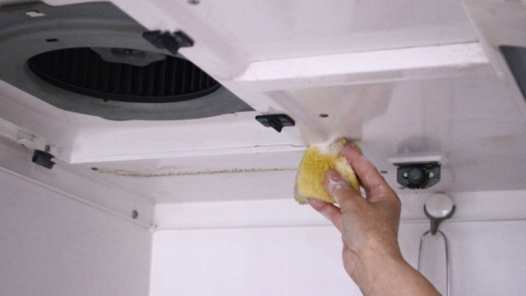 キッチンの換気扇をスポンジを使って掃除する様子