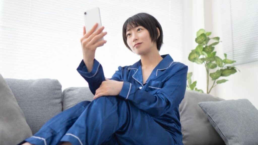自宅でスマホを見ながら快適に暮らす若い女性