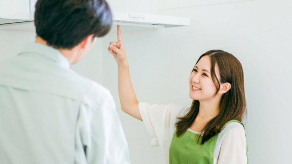 業者に換気扇の質問をする若い女性