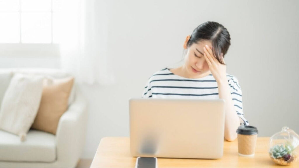 パソコン前で体調が悪そうな若い女性