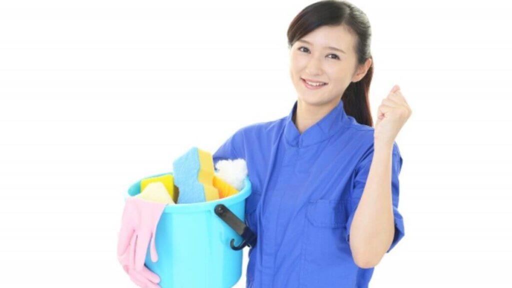 掃除を持ち笑顔のハウスクリーニング業者の女性