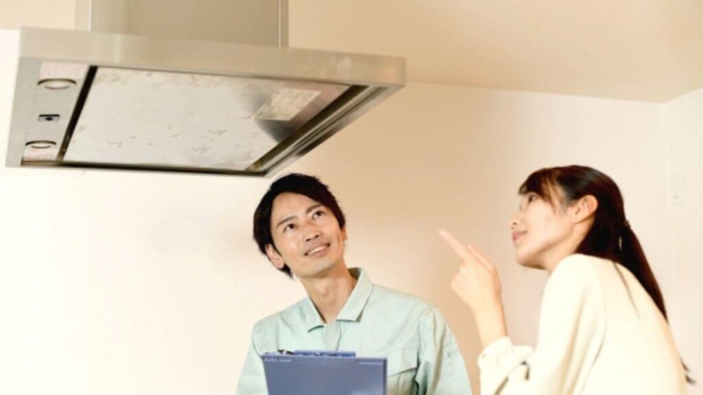 業者の男性に換気扇についての質問をする女性