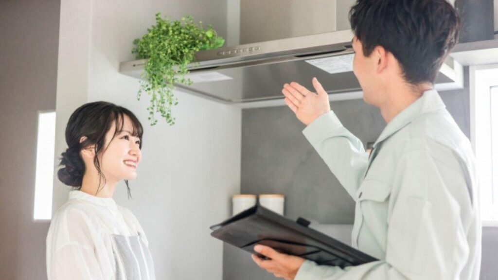 業者から換気扇の説明を受ける若い女性