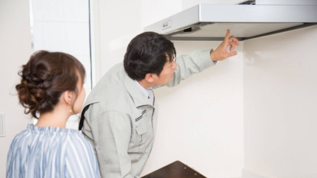 キッチンの換気扇をチェックする作業着姿の男性