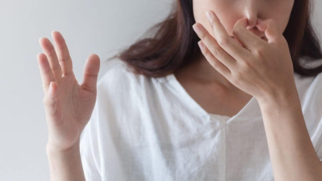 室内で鼻を押させている若い女性
