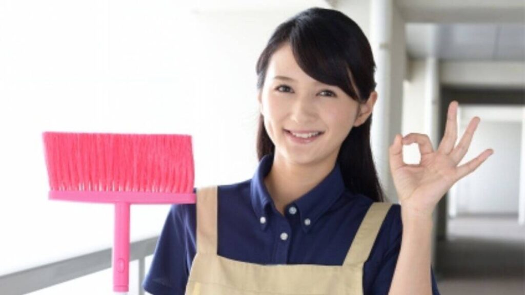 掃除道具を持ち笑顔の女性