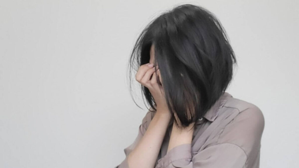 顔を手で塞ぎ体調の悪そうな主婦
