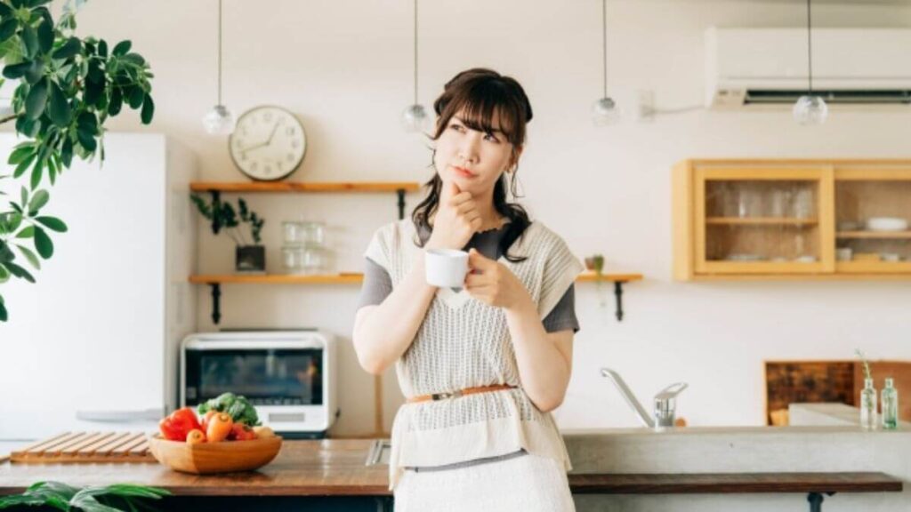 コーヒーカップを持ち考える主婦