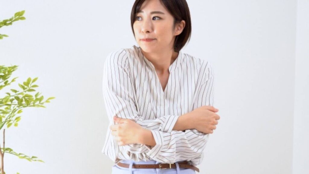 室内で体を丸め寒そうにする若い女性