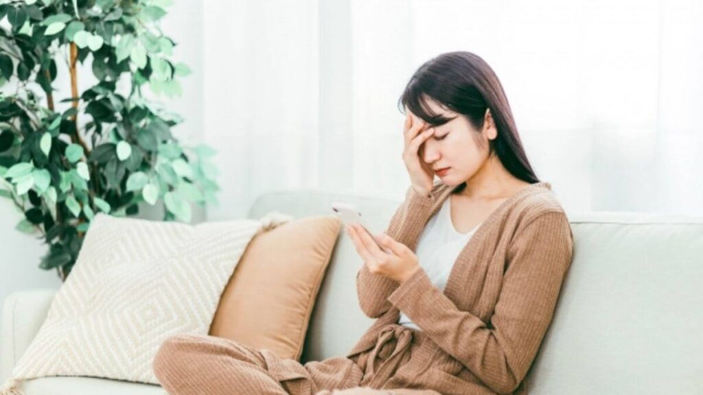 ソファーに座り頭をかける若い女性
