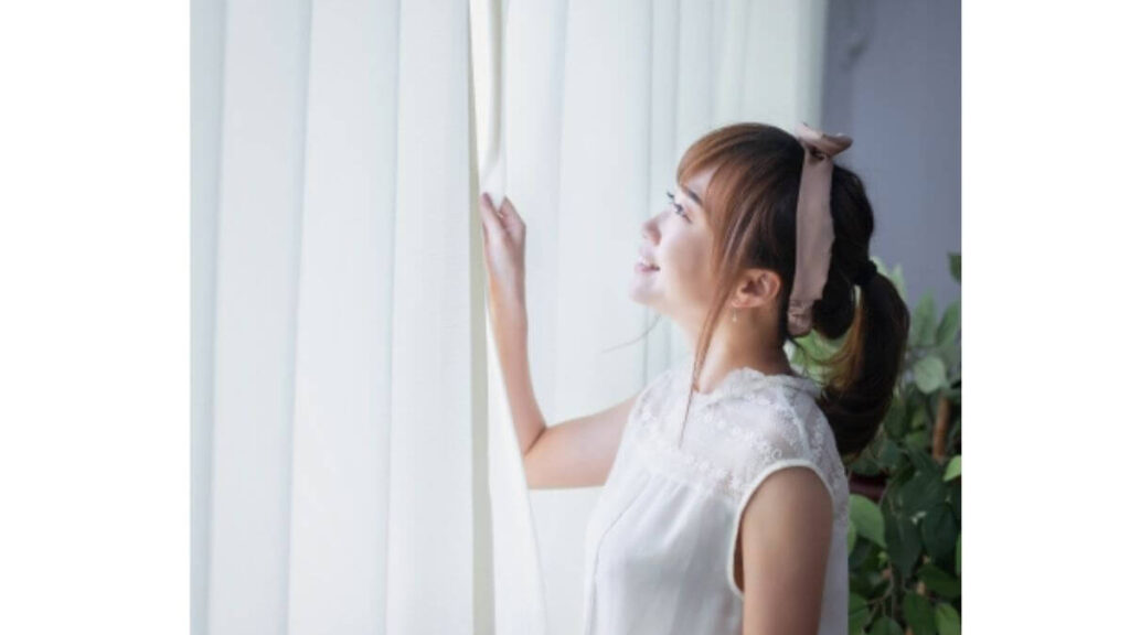 部屋を換気して笑顔の若い女性