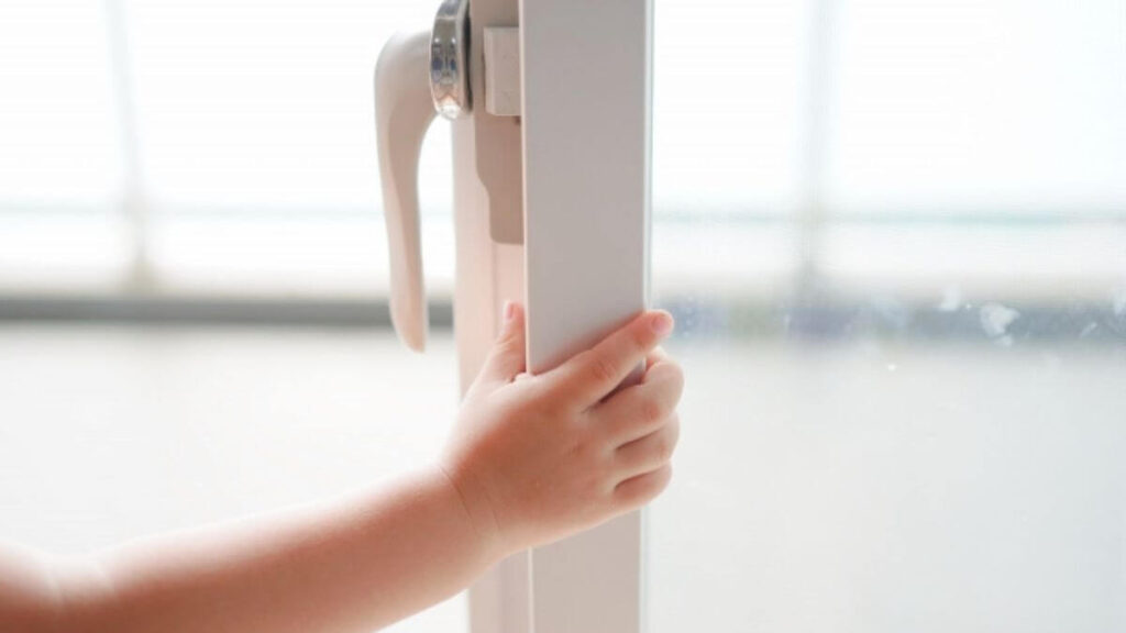 窓枠を触る小さい子供