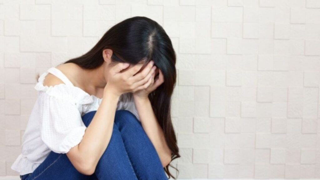 床に座って顔をおさえる主婦